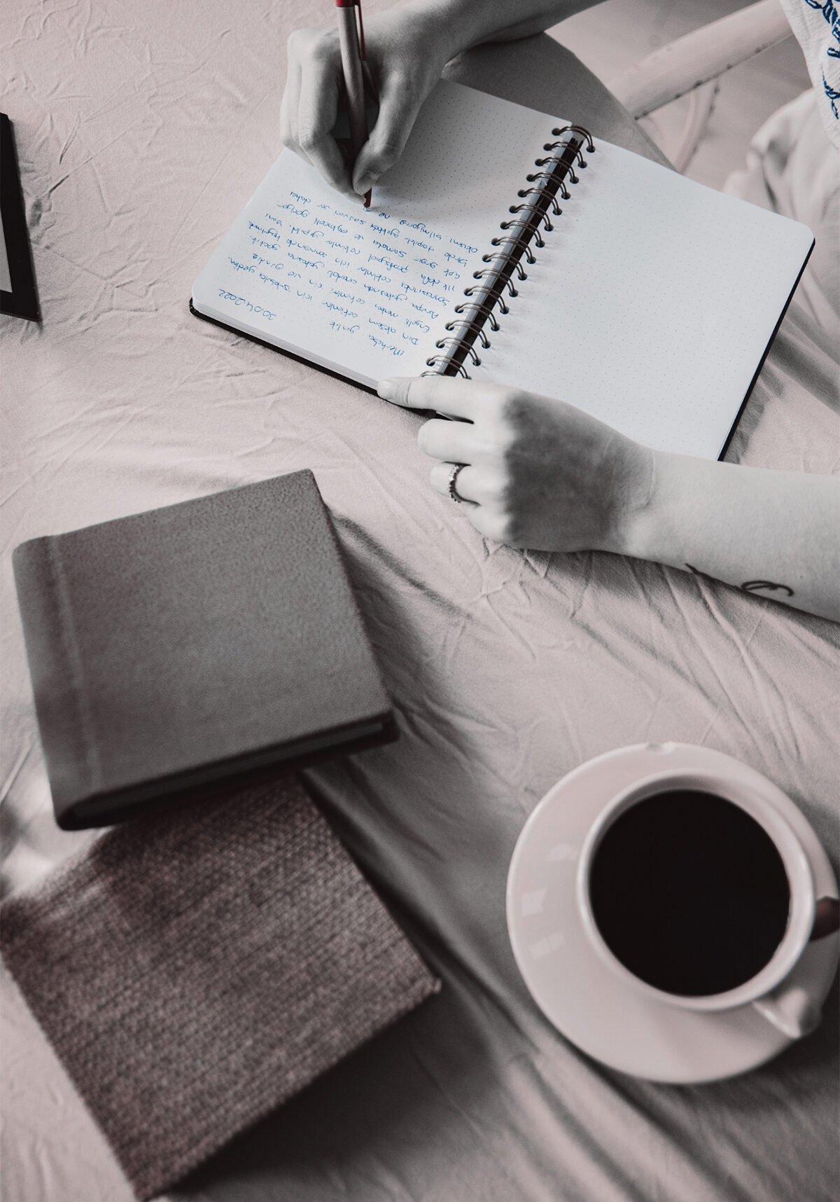 Woman Writing on notebook - About J. Harrington